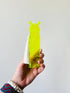 Hand holding a yellow ogre shaped bookmark on a plain background
