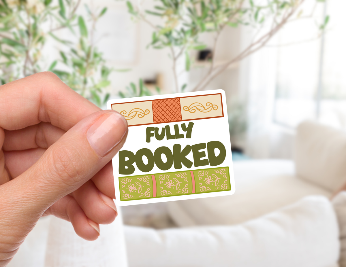 A hand holds a small rectangular sticker that reads &