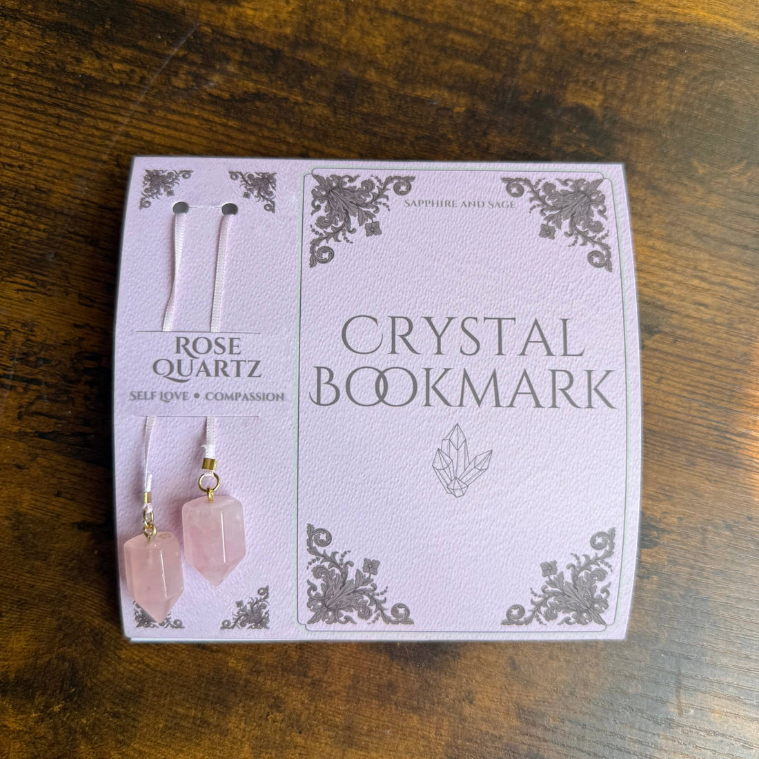 Rose Quartz crystal bookmark packaging on a wooden surface