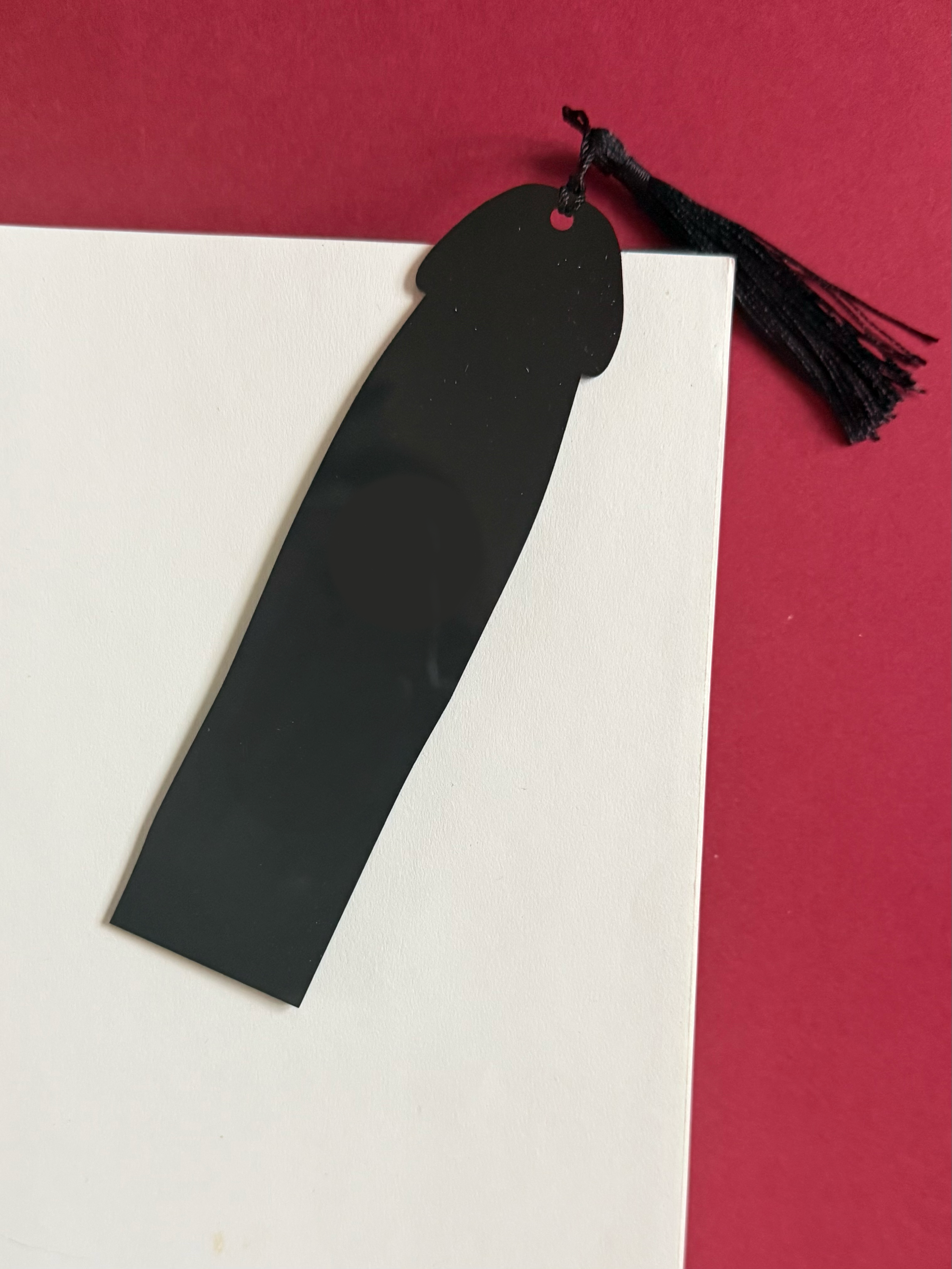 Black bookmark with tassel on a white and red background