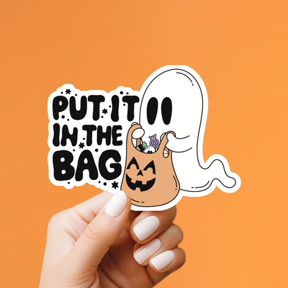 A hand with white manicured nails holds a die-cut sticker against a solid orange background. The sticker features the text &