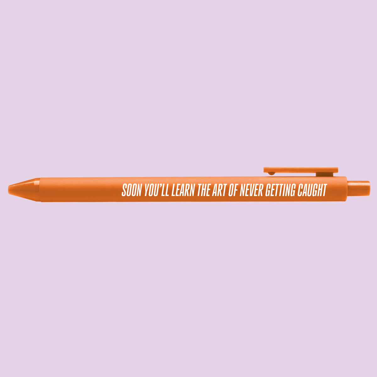 Art of Never Getting Caught pen flat lay — orange jotter gel pen for desk and journaling by indie artist MangoIllustrated