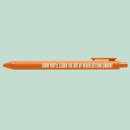 Art of Never Getting Caught pen flat lay — funny pop culture desk pen and stationery gift by indie artist MangoIllustrated