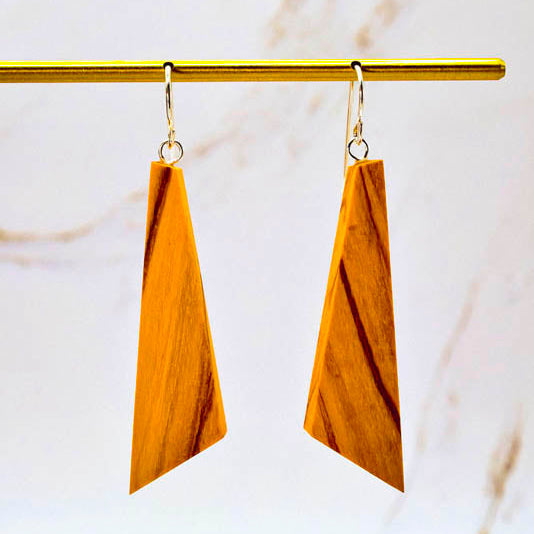 Wooden earrings on a gold hook against a marble background