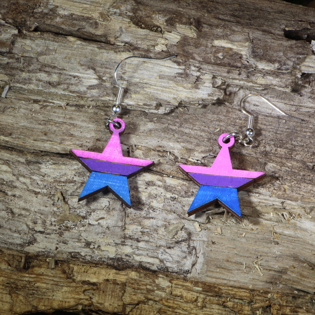 Hand-painted wooden bisexual pride star dangle earrings featuring pink, purple, and blue bisexual flag stripes, hypoallergenic sterling silver hooks, and lightweight LGBTQ+ pride jewelry for bisexual pride celebrations and queer accessory lovers by Cate&