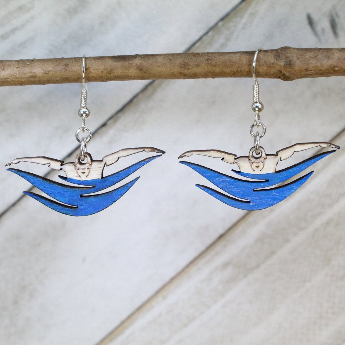 Hand-painted wooden butterfly stroke swimmer dangle earrings featuring a dynamic swimmer silhouette with extended arms and water motion detailing and hypoallergenic sterling silver hooks, lightweight jewelry for swimmers and competitive swim enthusiasts by Cate’s Concepts
