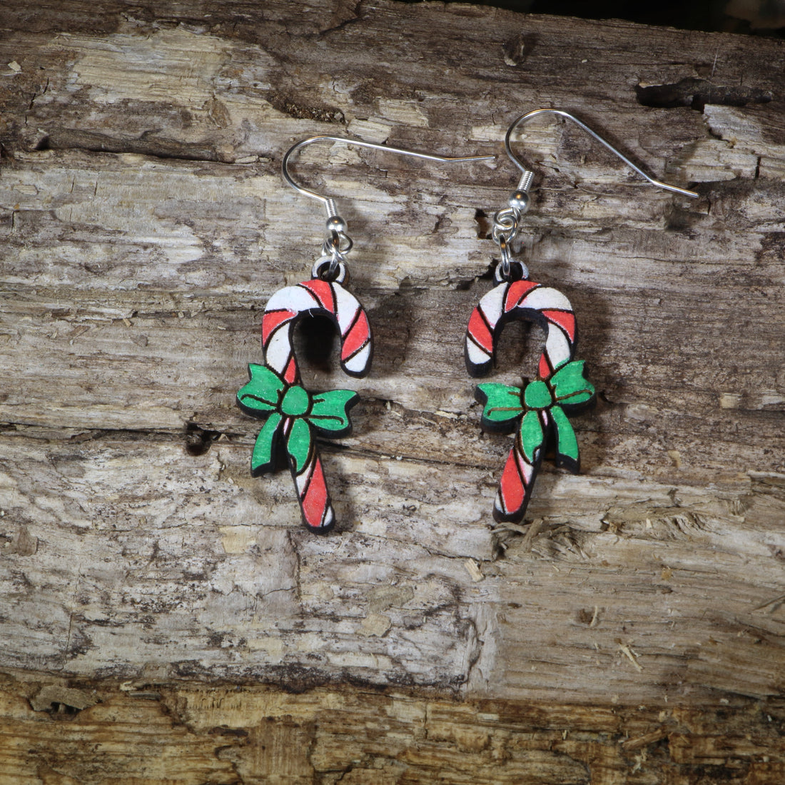 Hand-painted wooden candy cane with bow dangle earrings featuring festive red and white candy canes accented with a holiday bow, hypoallergenic sterling silver hooks, and lightweight Christmas jewelry for holiday celebrations by Cate&