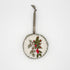 Ethically made by Syrian Refugees, this circular felt and hand embroidered ornament has a green ribbon, and red white and green cedar and berry motif, flat lay