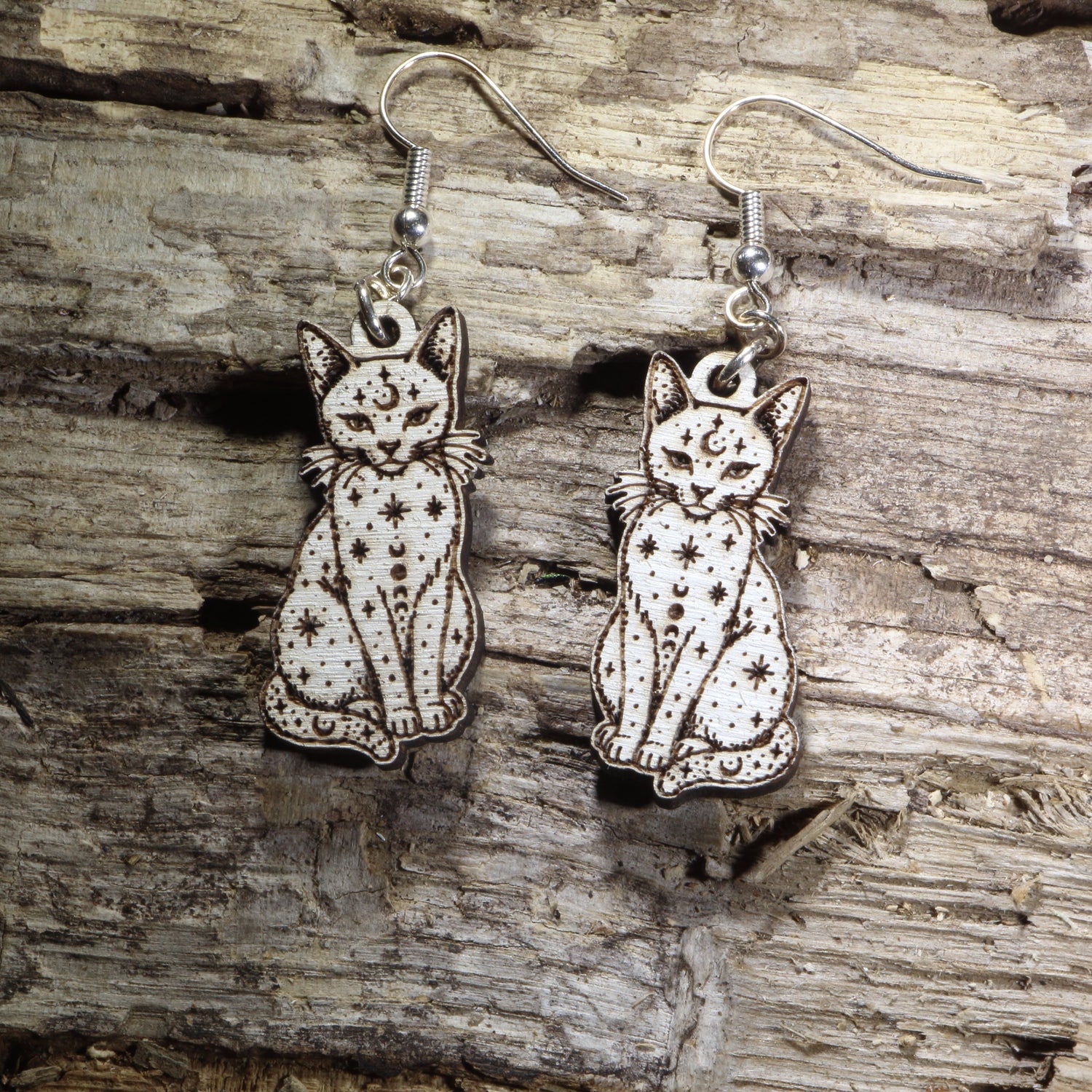 Handcrafted celestial cat wooden dangle earrings featuring an elegant cat silhouette adorned with moon phases, stars, and celestial details. Lightweight laser-cut wooden earrings with hypoallergenic .925 sterling silver hooks, perfect for cat lovers, witchy fashion, celestial jewelry collectors, moon enthusiasts, gothic style, and mystical handmade accessories.