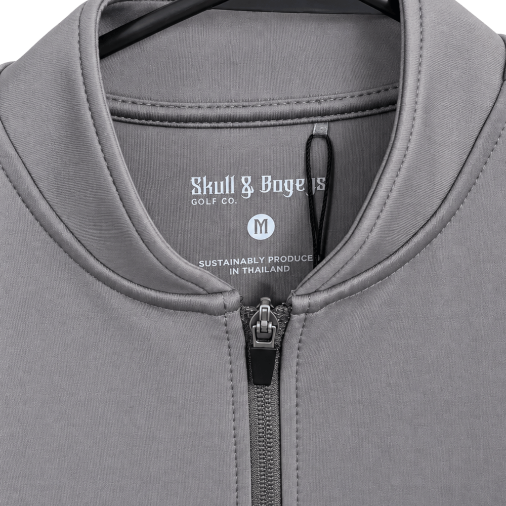 Close-up of a gray zip-up quarter-length shirt by Skull &amp; Boggs Golf Co, showing the collar, zipper, and inner neck label.
