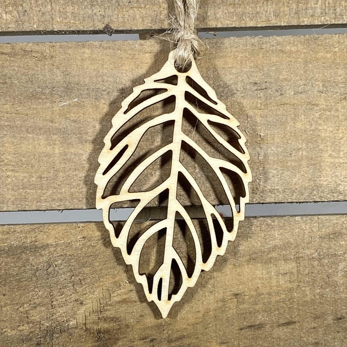 Hand-painted wooden cutout leaf Christmas ornament featuring an intricate nature-inspired leaf silhouette with detailed vein cutouts, elegant holiday decor for nature lovers and botanical enthusiasts by Cate’s Concepts