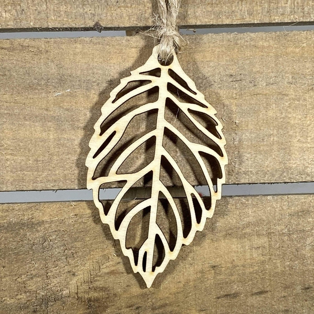 Hand-painted wooden cutout leaf Christmas ornament featuring an intricate nature-inspired leaf silhouette with detailed vein cutouts, elegant holiday decor for nature lovers and botanical enthusiasts by Cate’s Concepts
