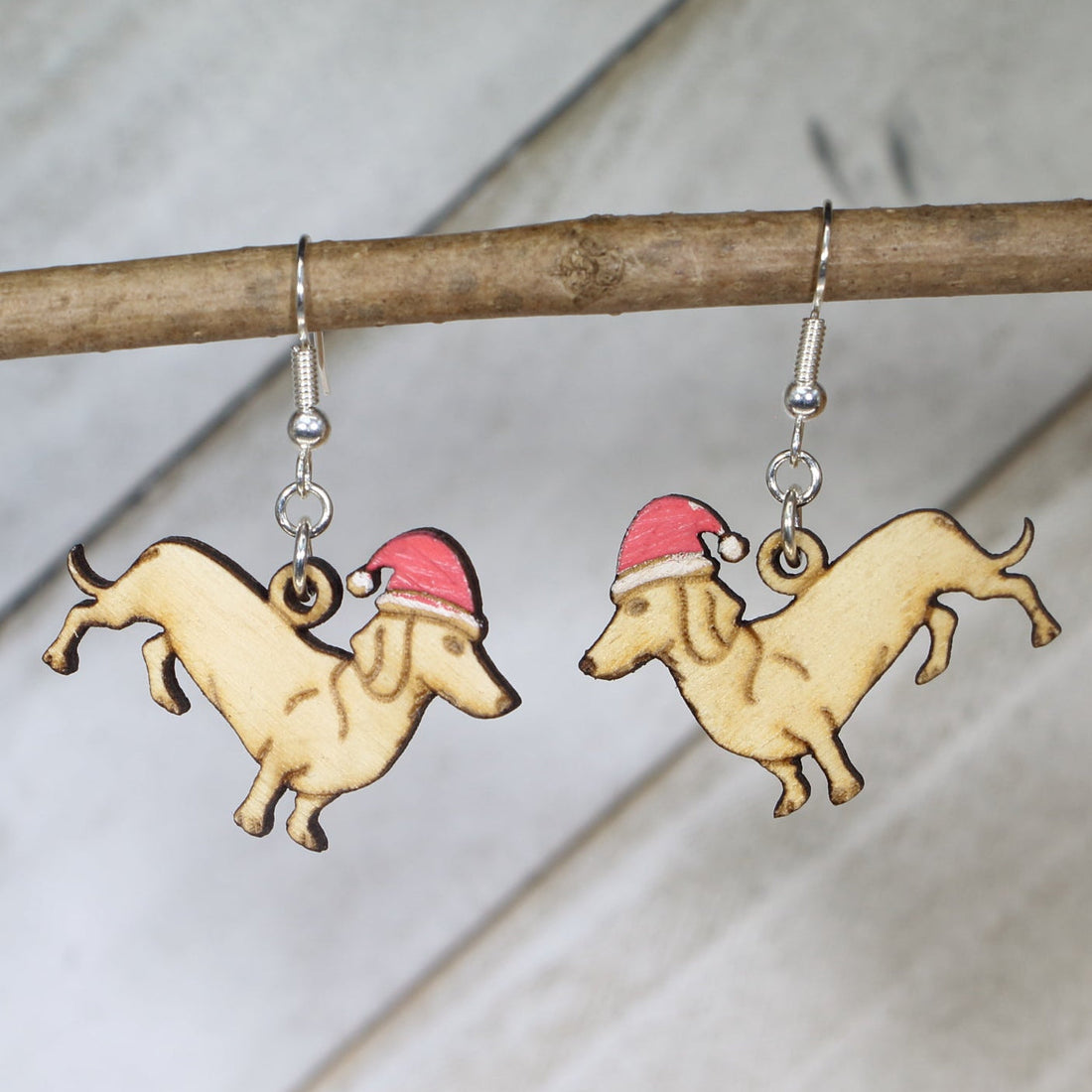 Hand-painted wooden dachshund Santa hat dangle earrings featuring a long-bodied wiener dog design wearing a festive Santa hat and hypoallergenic sterling silver hooks, lightweight jewelry for dog lovers and Christmas enthusiasts