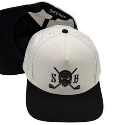 A structured baseball cap shown from the front and back. The front panel is off-white with a black embroidered skull and crossed golf clubs logo flanked by the letters &