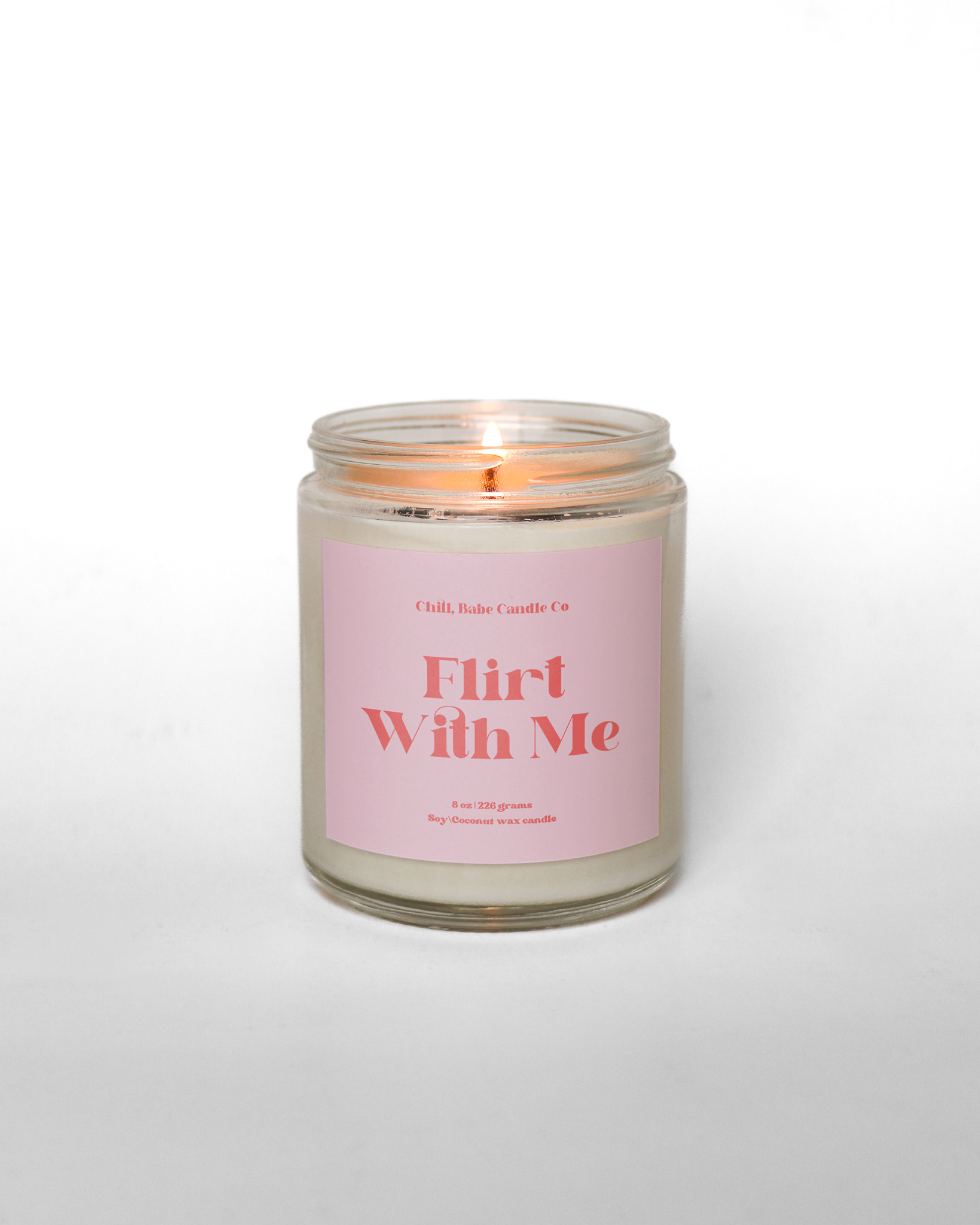 Lit Flirt with me candle in front of a white background