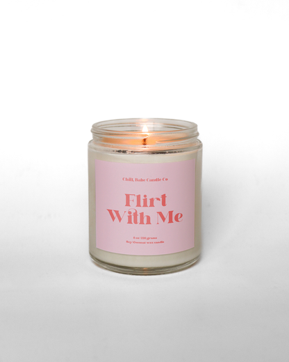 Lit Flirt with me candle in front of a white background