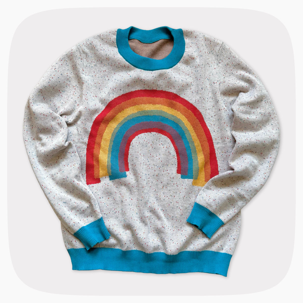 A gray graphic knit sweater with a sprinkled pattern and a rainbow on the front center.