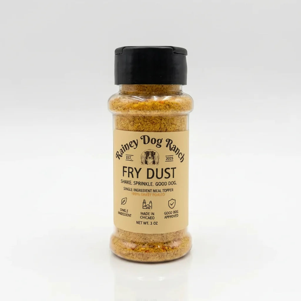 A bottle of Rainey Dog Ranch Fry Dust seasoning with a black cap and beige label, filled with a golden-brown spice blend, set against a clean white background.