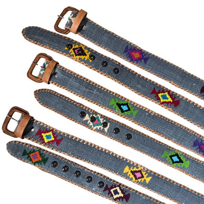 Five denim-style belts with brown leather buckles and trim, decorated with colorful geometric beadwork, arranged diagonally on a white background.