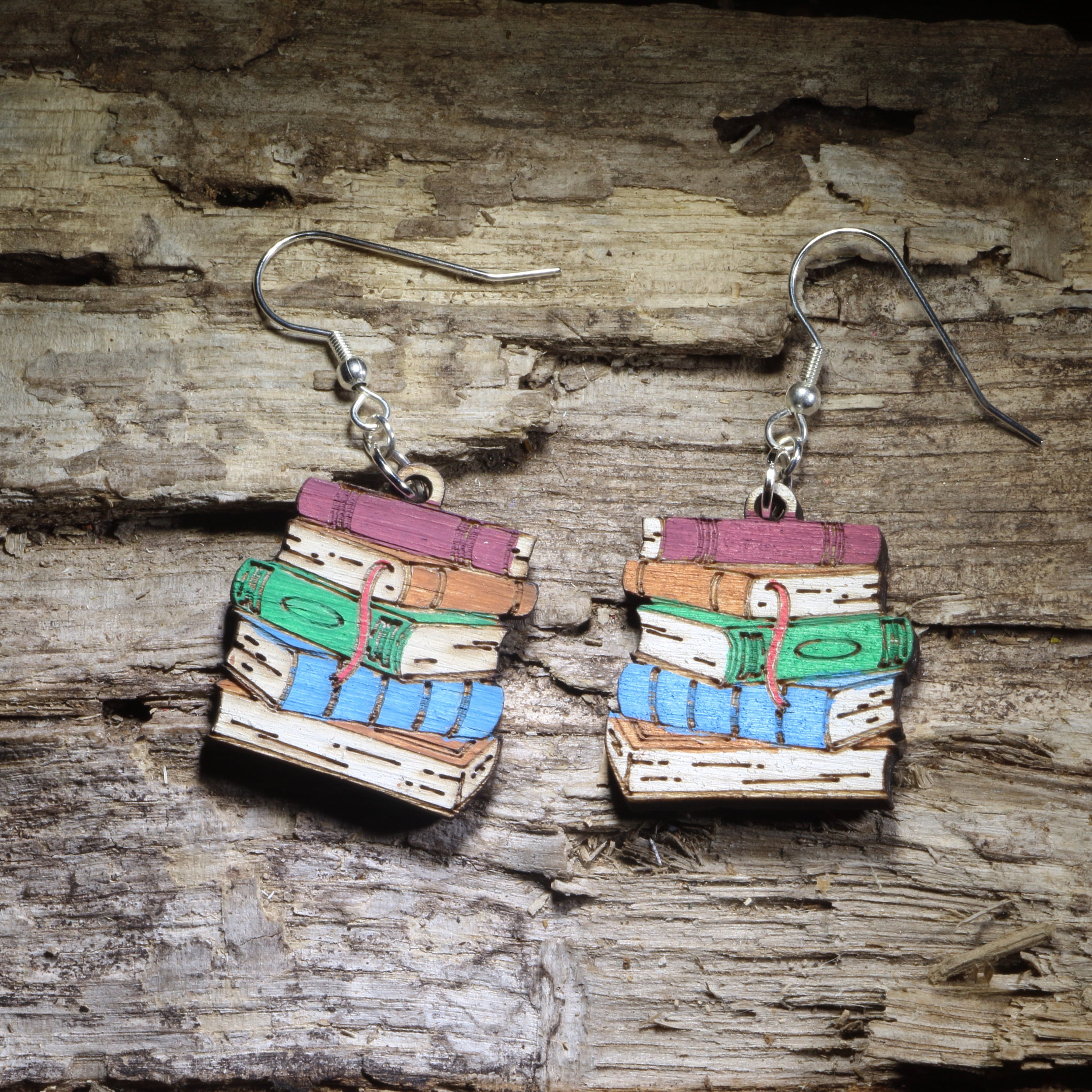Hand-painted book stack wooden dangle earrings featuring a colorful pile of classic books. Lightweight literary jewelry perfect for librarians, teachers, readers, book lovers, writers, and thoughtful bookish gifts.