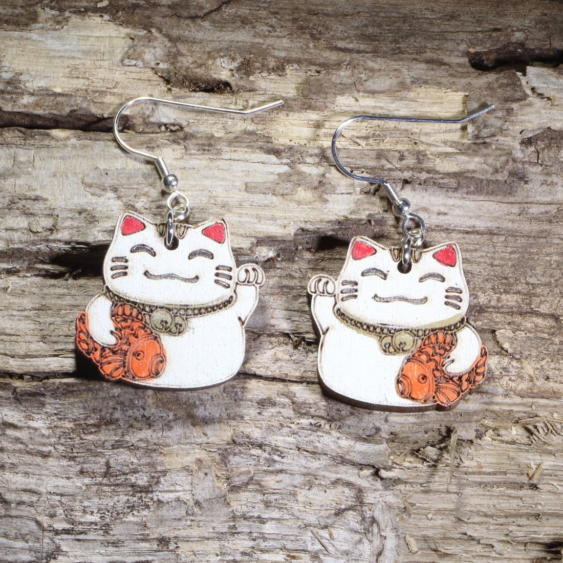 Hand-painted wooden Maneki-neko lucky cat dangle earrings featuring a smiling white Japanese lucky cat holding an orange koi fish on hypoallergenic .925 sterling silver hooks. Lightweight cat lover jewelry inspired by Japanese culture for cat enthusiasts, anime fans, and collectors of lucky cat accessories.