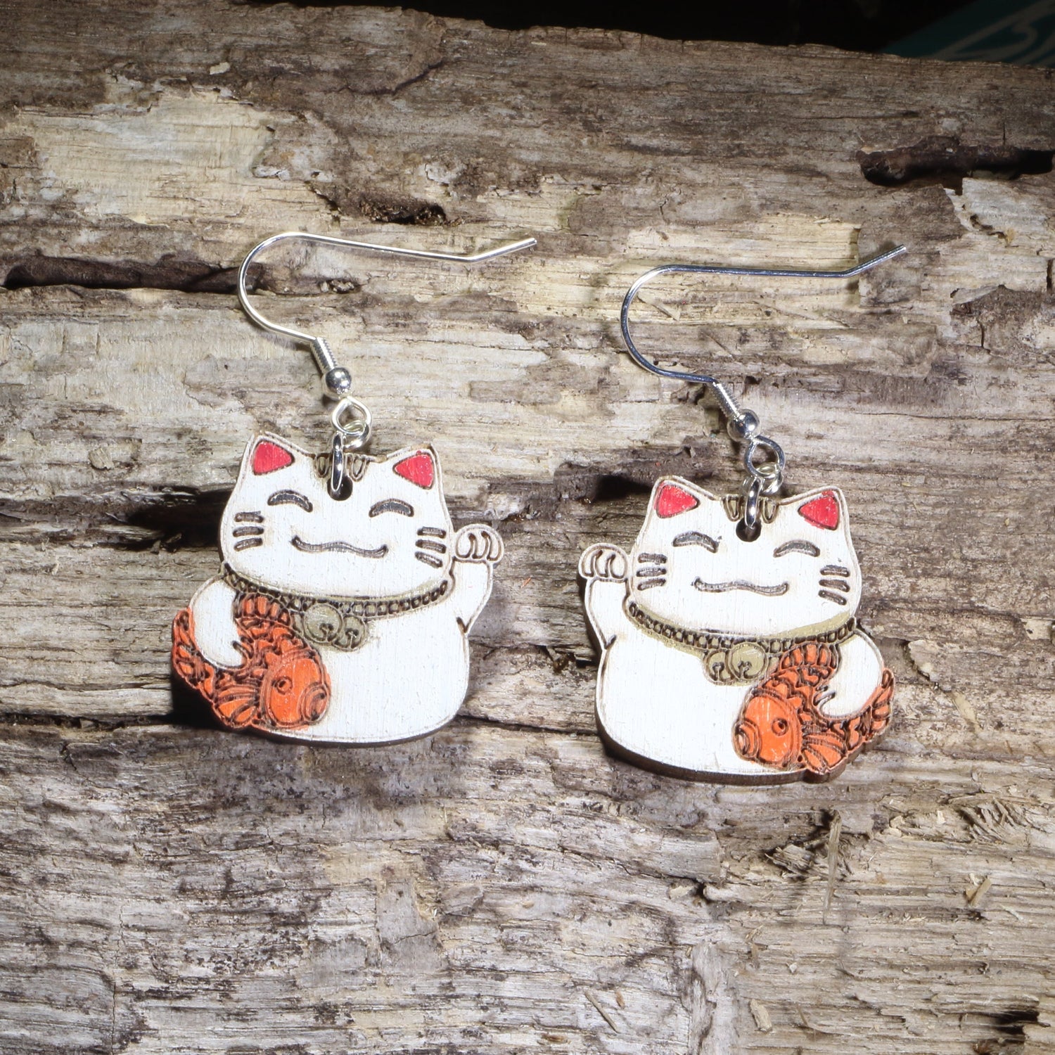 Hand-painted wooden Maneki-neko lucky cat dangle earrings featuring a smiling white Japanese lucky cat holding an orange koi fish on hypoallergenic .925 sterling silver hooks. Lightweight cat lover jewelry inspired by Japanese culture for cat enthusiasts, anime fans, and collectors of lucky cat accessories.