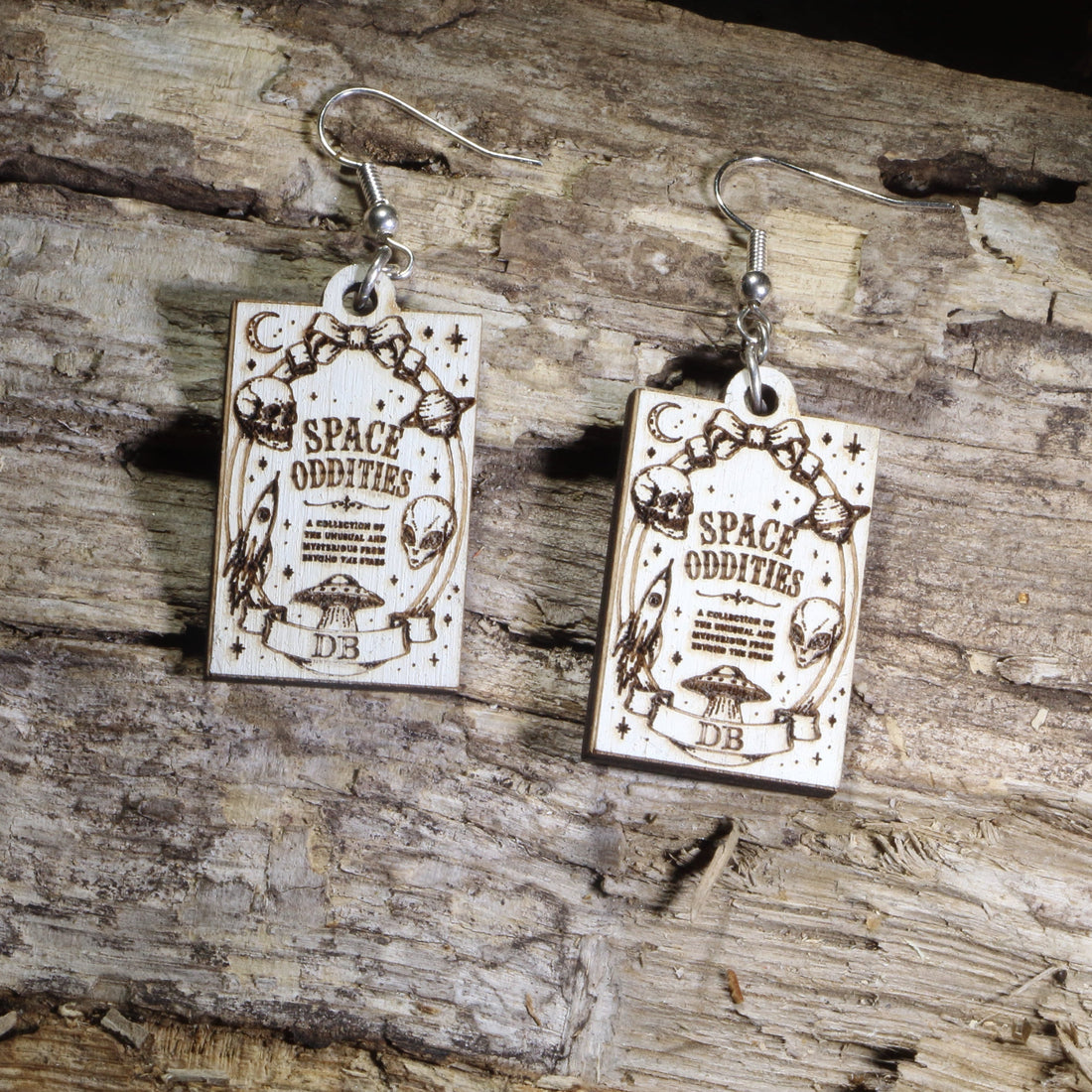 Hand-painted wooden Space Oddities book cover dangle earrings featuring a vintage-inspired sci-fi gothic book cover design on hypoallergenic .925 sterling silver hooks. Lightweight book lover jewelry for readers, science fiction fans, gothic literature enthusiasts, horror lovers, librarians, and collectors of unique literary accessories.