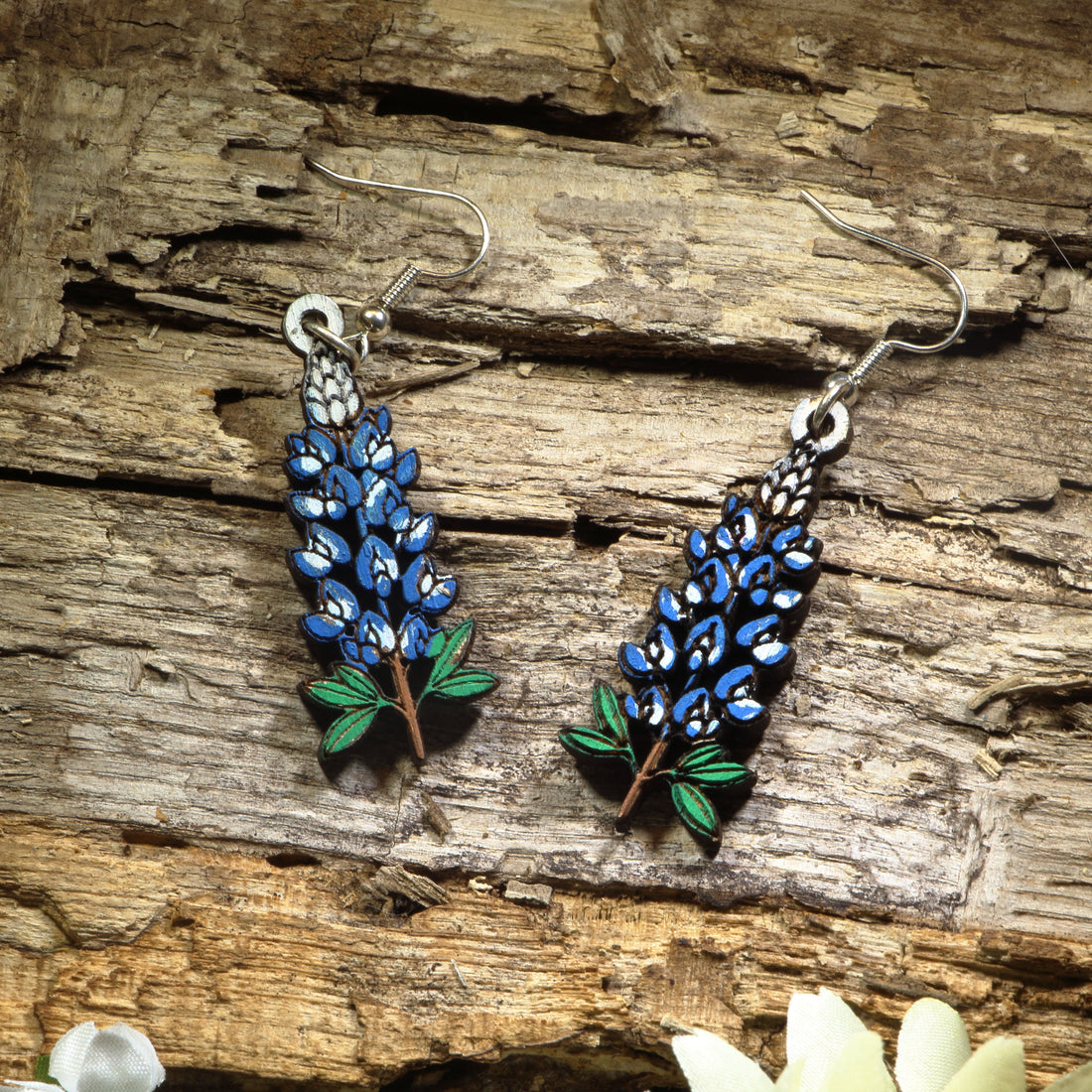 Hand-painted wooden Texas Bluebonnet dangle earrings featuring the iconic blue state flower of Texas with vibrant floral details. Crafted from lightweight wood with hypoallergenic .925 sterling silver hooks, these artisan earrings are perfect for Texas pride, wildflower lovers, spring festivals, Bluebonnet season, nature enthusiasts, travel souvenirs, and anyone who loves colorful botanical jewelry inspired by the Lone Star State.