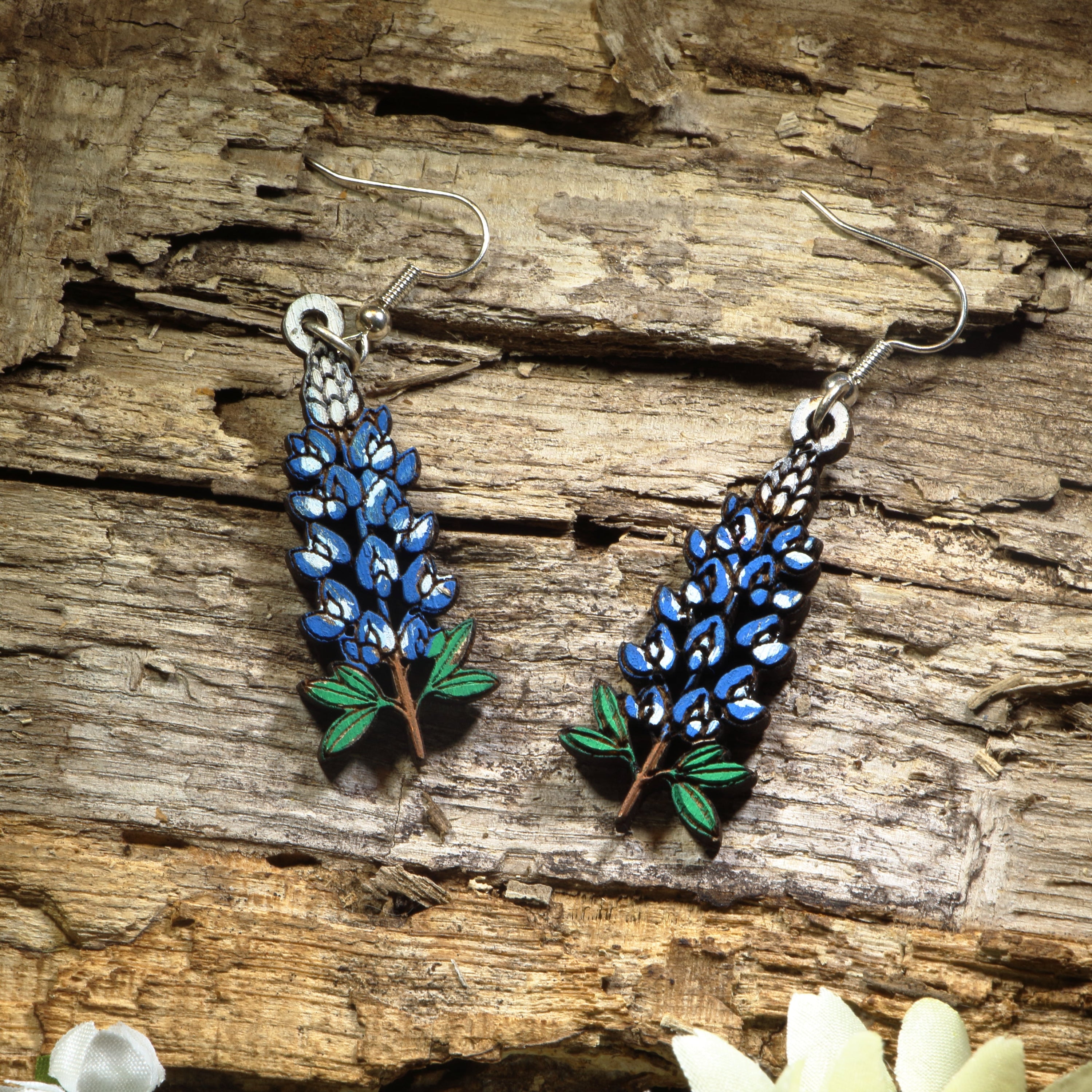 Hand-painted wooden Texas Bluebonnet dangle earrings featuring the iconic blue state flower of Texas with vibrant floral details. Crafted from lightweight wood with hypoallergenic .925 sterling silver hooks, these artisan earrings are perfect for Texas pride, wildflower lovers, spring festivals, Bluebonnet season, nature enthusiasts, travel souvenirs, and anyone who loves colorful botanical jewelry inspired by the Lone Star State.