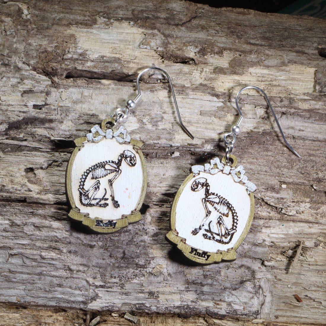 Hand-painted wooden cat skeleton cameo dangle earrings featuring an elegant feline skeleton framed in an ornate vintage cameo on hypoallergenic .925 sterling silver hooks. Lightweight gothic jewelry for cat lovers, Halloween enthusiasts, dark academia fans, veterinarians, anatomy enthusiasts, and collectors of spooky accessories.
