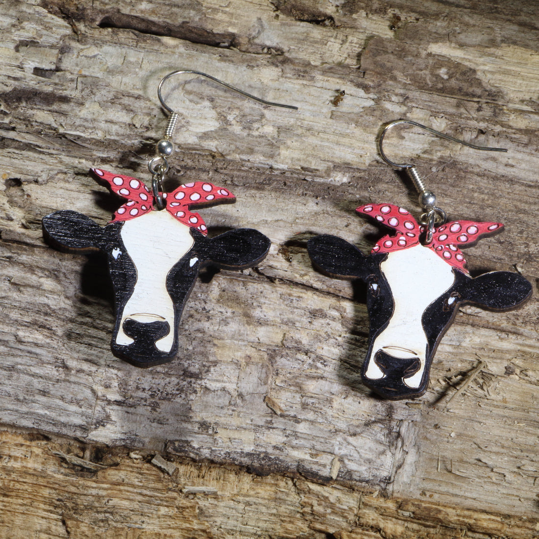 Hand-painted wooden cow head dangle earrings featuring black and white cow faces with red polka dot bandanas on hypoallergenic .925 sterling silver hooks. Lightweight farm animal jewelry perfect for cow lovers, ranch life, country style, and western fashion.