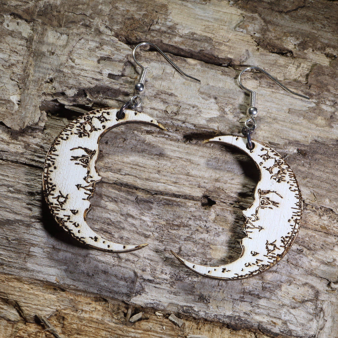 Hand-painted wooden crescent moon dangle earrings featuring engraved vintage moon face details on hypoallergenic .925 sterling silver hooks. Lightweight celestial jewelry perfect for moon lovers, astrology enthusiasts, witchy style, gothic fashion, and lunar-inspired accessories.