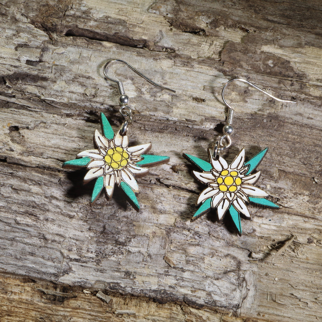 Hand-painted wooden edelweiss flower dangle earrings featuring white alpine blossoms with yellow centers and teal accents on hypoallergenic .925 sterling silver hooks. Lightweight floral jewelry perfect for nature lovers, hikers, alpine flower enthusiasts, Swiss and Austrian heritage, and botanical-inspired accessories.