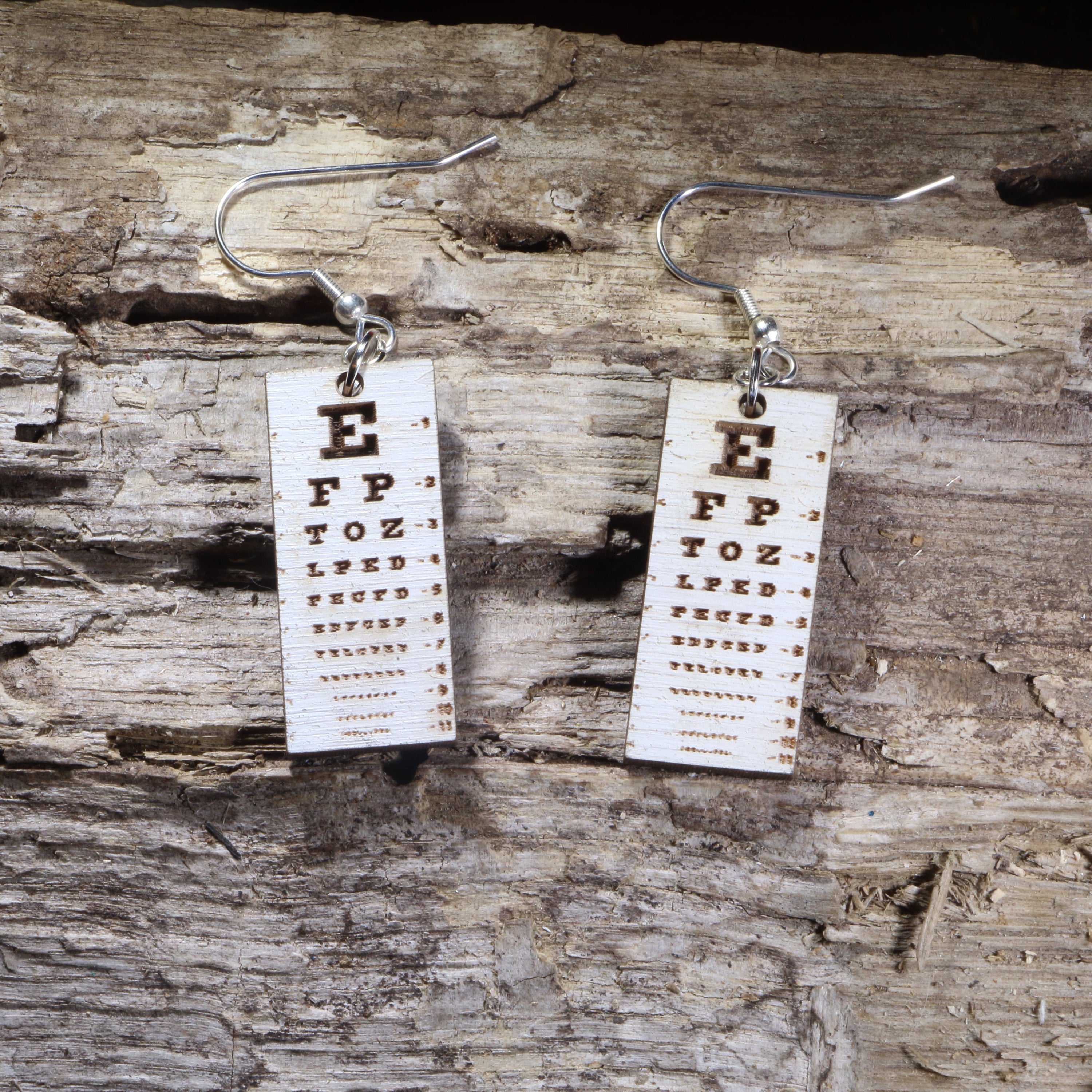 Hand-painted wooden eye chart dangle earrings featuring a classic vision test chart design on lightweight wood with hypoallergenic .925 sterling silver hooks. Perfect for optometrists, ophthalmologists, eye doctors, optometry students, vision care professionals, and unique medical-themed jewelry lovers.