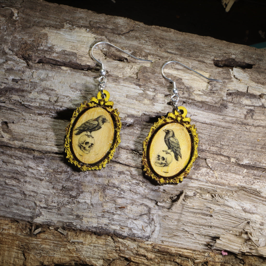Hand-painted wooden gothic raven cameo dangle earrings featuring a black raven framed in an ornate vintage cameo design on hypoallergenic .925 sterling silver hooks. Lightweight dark academia jewelry for raven lovers, gothic fashion enthusiasts, Edgar Allan Poe fans, Halloween lovers, and collectors of Victorian-inspired accessories.