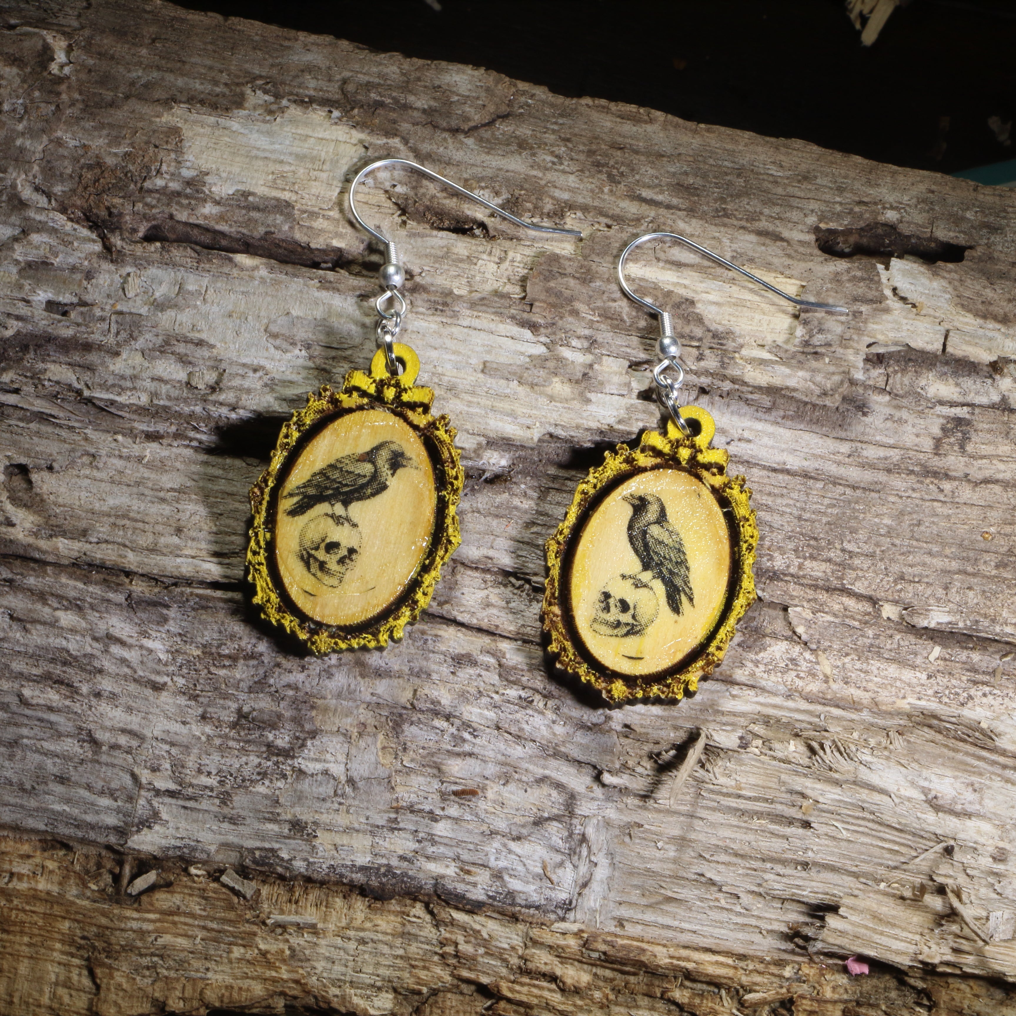 Hand-painted wooden gothic raven cameo dangle earrings featuring a black raven framed in an ornate vintage cameo design on hypoallergenic .925 sterling silver hooks. Lightweight dark academia jewelry for raven lovers, gothic fashion enthusiasts, Edgar Allan Poe fans, Halloween lovers, and collectors of Victorian-inspired accessories.