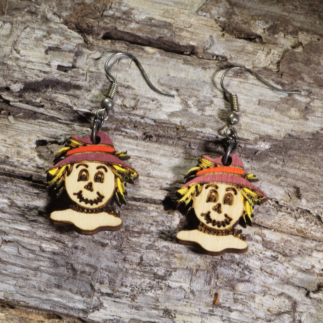 Hand-painted wooden scarecrow dangle earrings featuring smiling scarecrow faces with straw hair and burgundy hats on hypoallergenic .925 sterling silver hooks. Lightweight fall harvest jewelry perfect for autumn lovers, Halloween, and Thanksgiving.