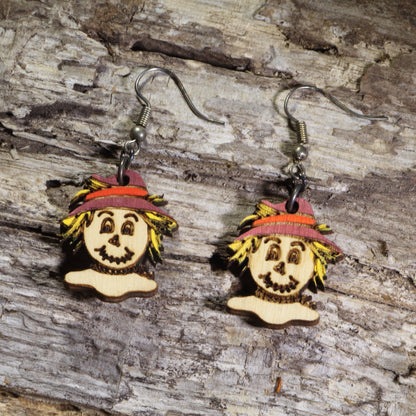 Hand-painted wooden scarecrow dangle earrings featuring smiling scarecrow faces with straw hair and burgundy hats on hypoallergenic .925 sterling silver hooks. Lightweight fall harvest jewelry perfect for autumn lovers, Halloween, and Thanksgiving.