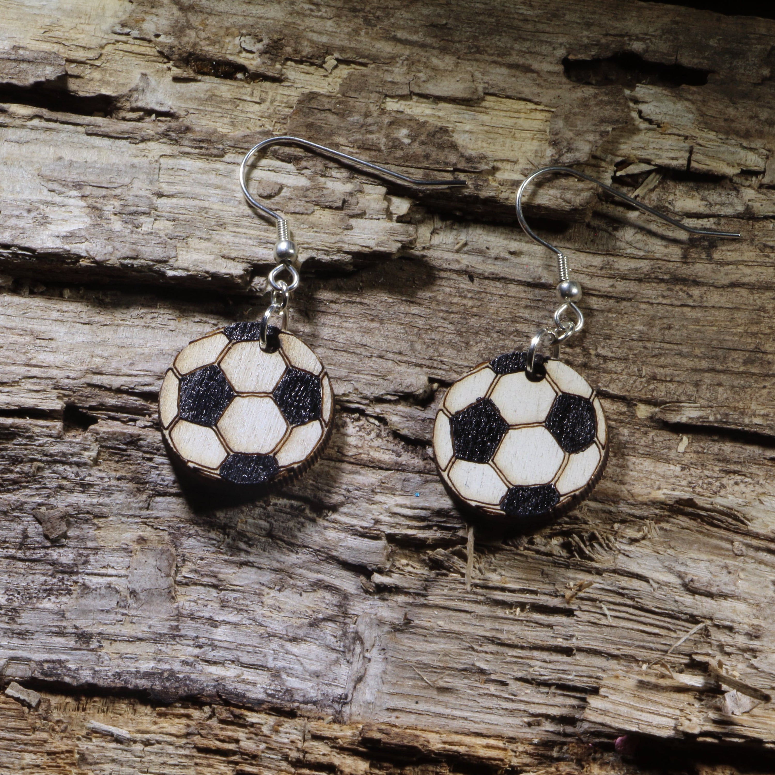 Hand-painted wooden soccer ball dangle earrings featuring the classic black-and-white soccer ball design. Lightweight sports earrings with hypoallergenic .925 sterling silver hooks, perfect for soccer players, coaches, referees, team moms, sports fans, and anyone who loves the world&