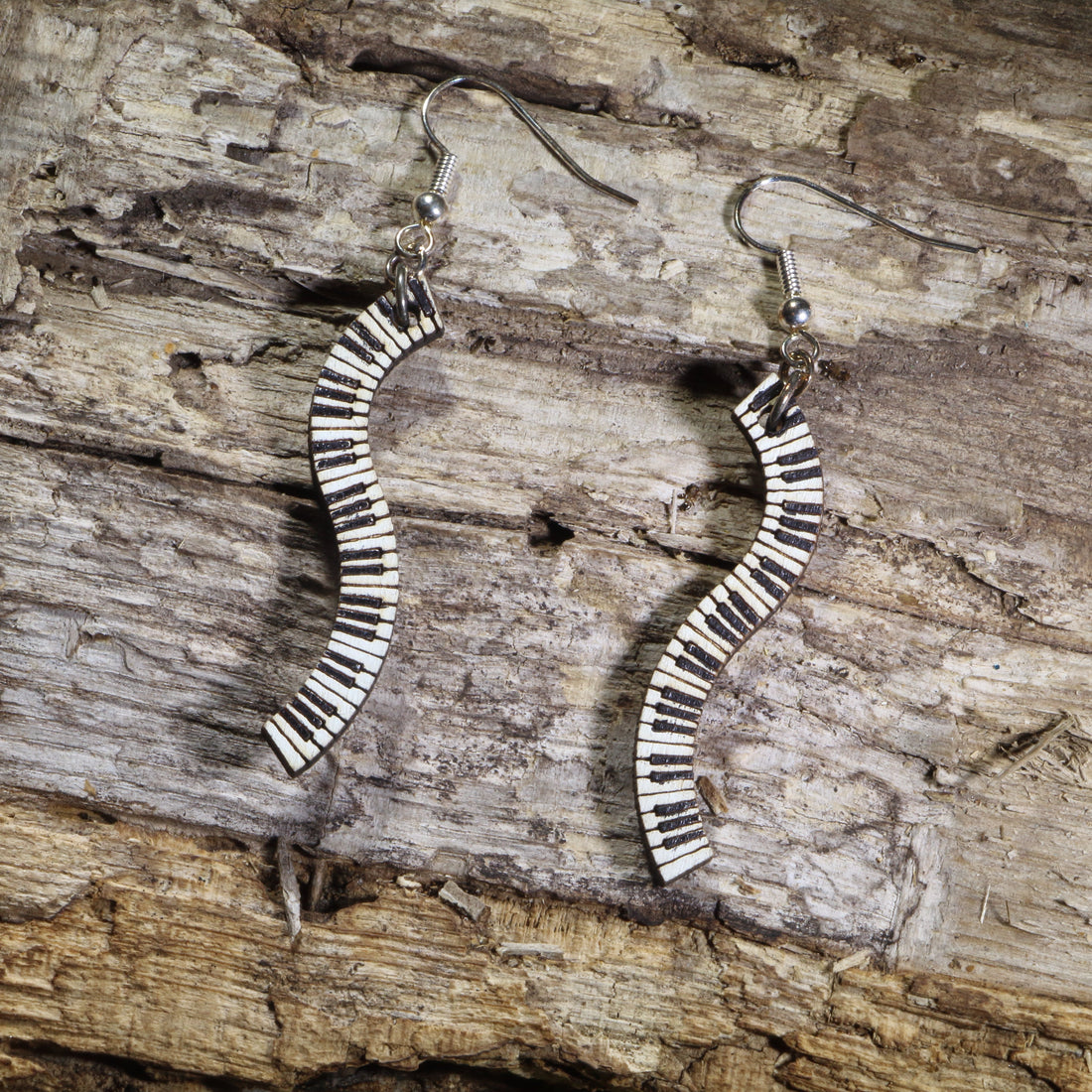 Hand-painted wooden wavy piano keyboard dangle earrings featuring flowing black and white piano keys on hypoallergenic .925 sterling silver hooks. Lightweight music jewelry perfect for pianists, piano teachers, musicians, music students, and classical music lovers.