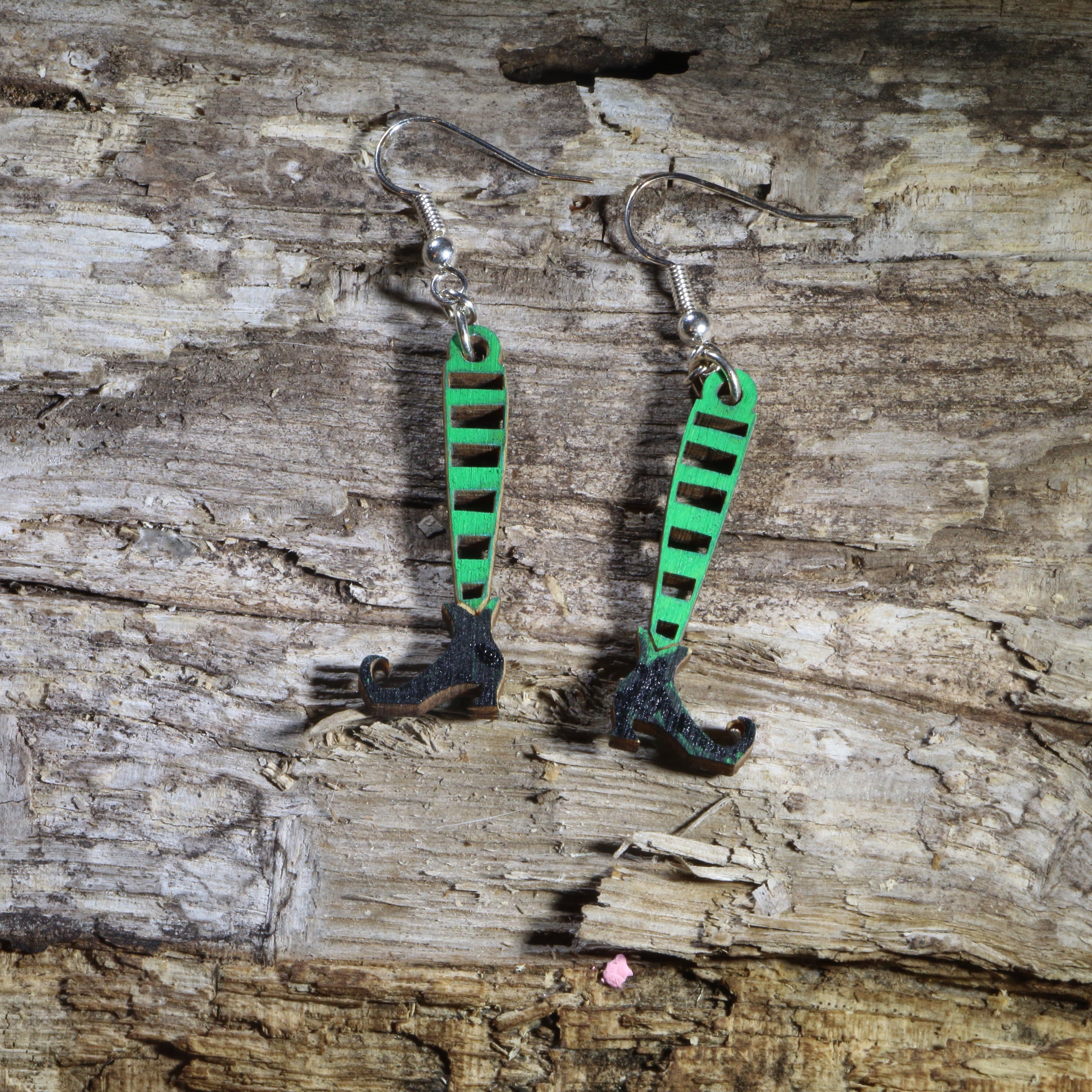 Hand-painted wooden witch legs dangle earrings featuring striped stockings, pointed black witch shoes, and a whimsical Halloween design. Lightweight Halloween earrings with hypoallergenic .925 sterling silver hooks, perfect for spooky season, Halloween parties, witch lovers, trick-or-treat events, and festive fall outfits.