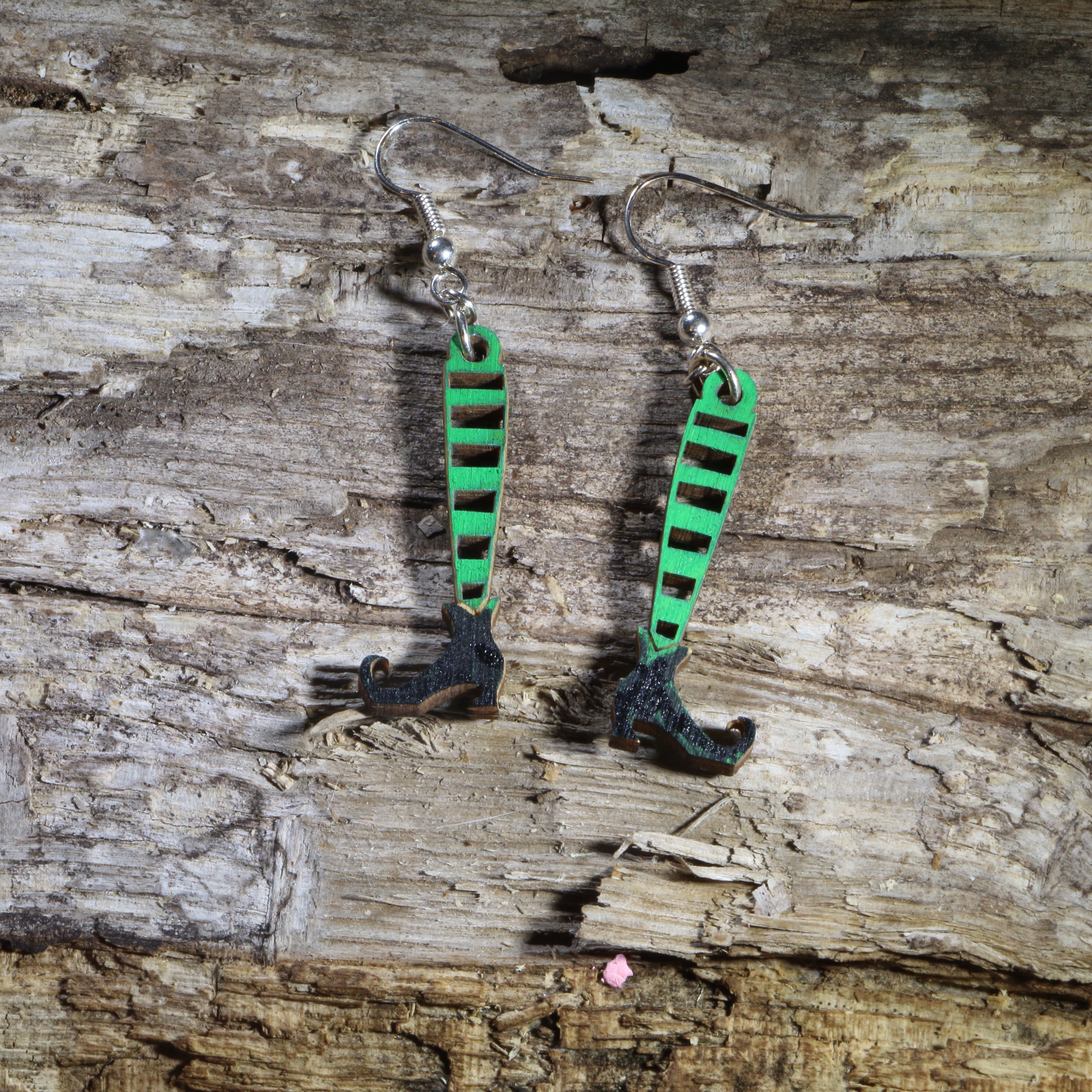Hand-painted wooden witch legs dangle earrings featuring striped stockings, pointed black witch shoes, and a whimsical Halloween design. Lightweight Halloween earrings with hypoallergenic .925 sterling silver hooks, perfect for spooky season, Halloween parties, witch lovers, trick-or-treat events, and festive fall outfits.