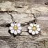 Handcrafted Smiley Daisy wooden dangle earrings featuring cheerful smiling daisy flowers with bright, playful details. Lightweight laser-cut wooden earrings with hypoallergenic .925 sterling silver hooks, perfect for flower lovers, retro 70s fashion, happy aesthetic, spring accessories, cottagecore style, and fun everyday jewelry.