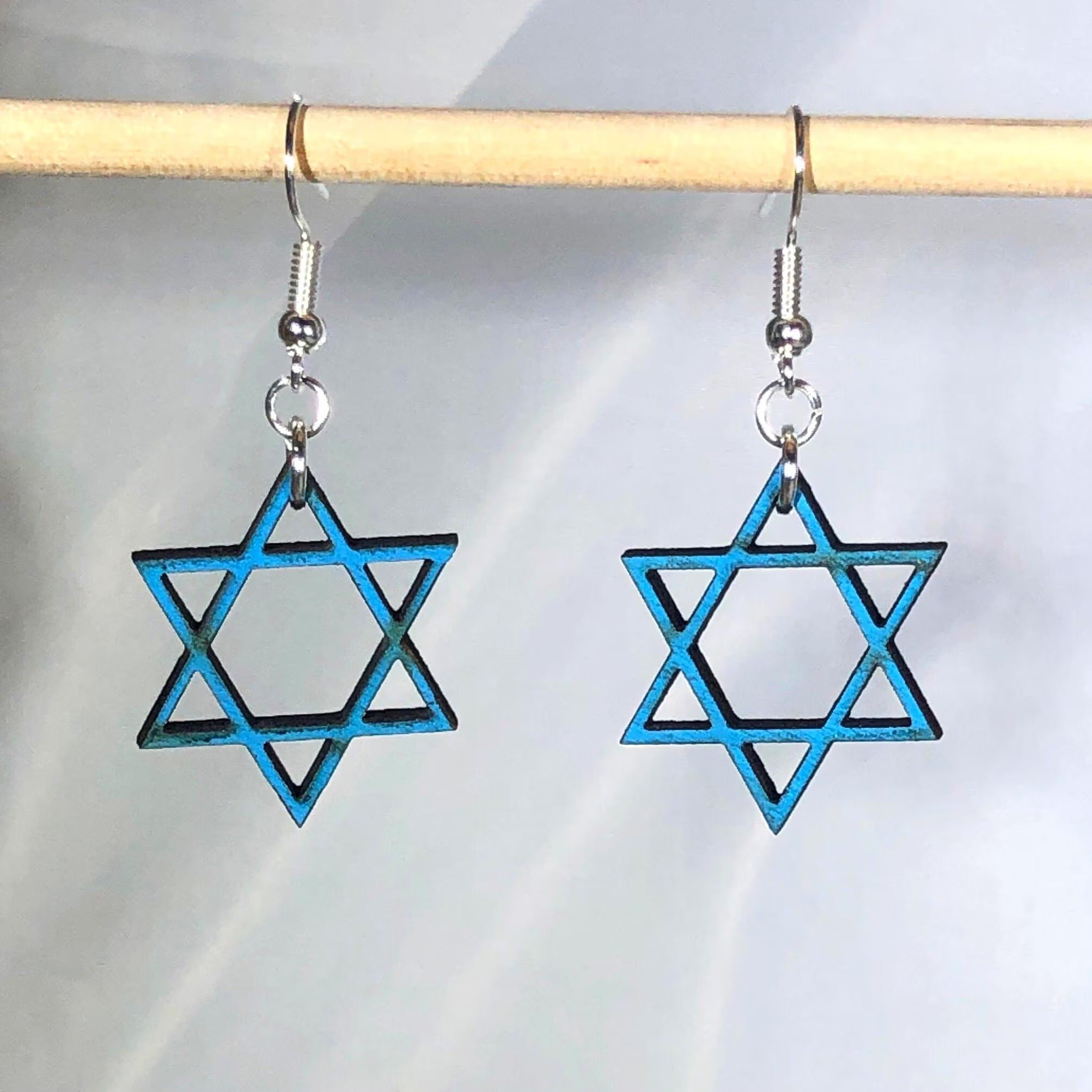 Handcrafted Star of David wooden dangle earrings featuring a hand-painted blue six-pointed Jewish star design. Lightweight laser-cut wooden earrings with hypoallergenic .925 sterling silver hooks, perfect for Jewish faith, Hanukkah celebrations, synagogue events, Bat Mitzvah gifts, Jewish heritage, and handmade religious jewelry.