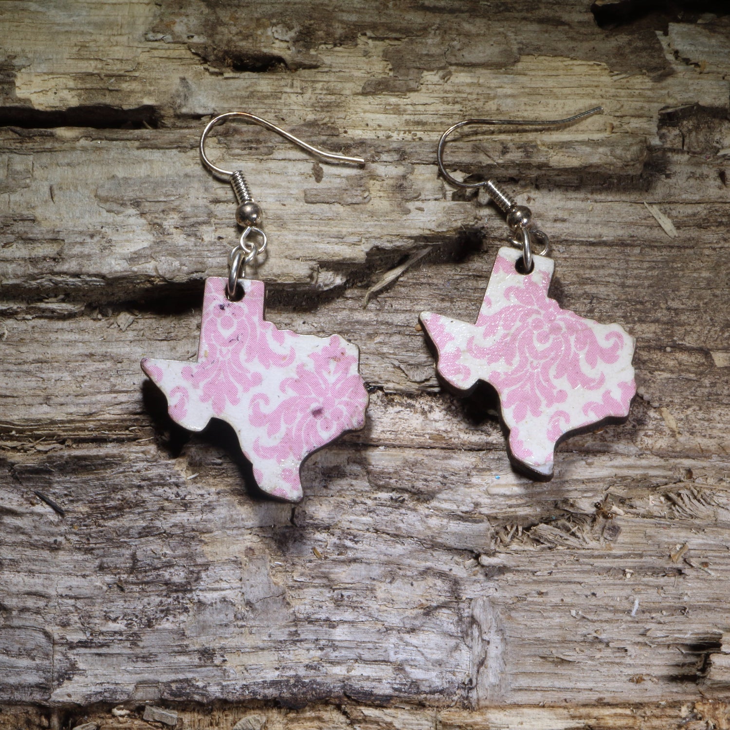Handcrafted Texas-shaped wooden dangle earrings featuring a soft pink floral pattern. Lightweight hand-painted wooden earrings with hypoallergenic .925 sterling silver hooks, perfect for Texas lovers, Southern style, country fashion, spring outfits, Texas gifts, and anyone who loves elegant Lone Star State jewelry.