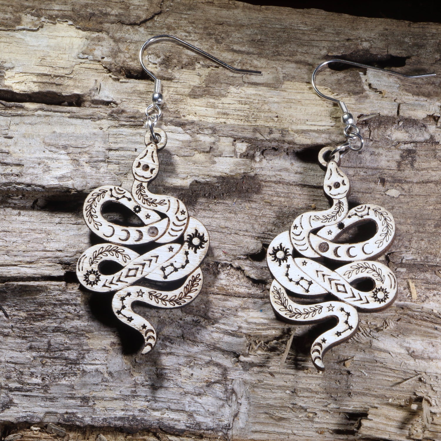Handcrafted celestial snake wooden dangle earrings featuring engraved moon phases, stars, constellations, and botanical details. Lightweight wooden serpent earrings with hypoallergenic .925 sterling silver hooks, perfect for witchy jewelry lovers, celestial fashion, gothic style, and nature-inspired accessories.