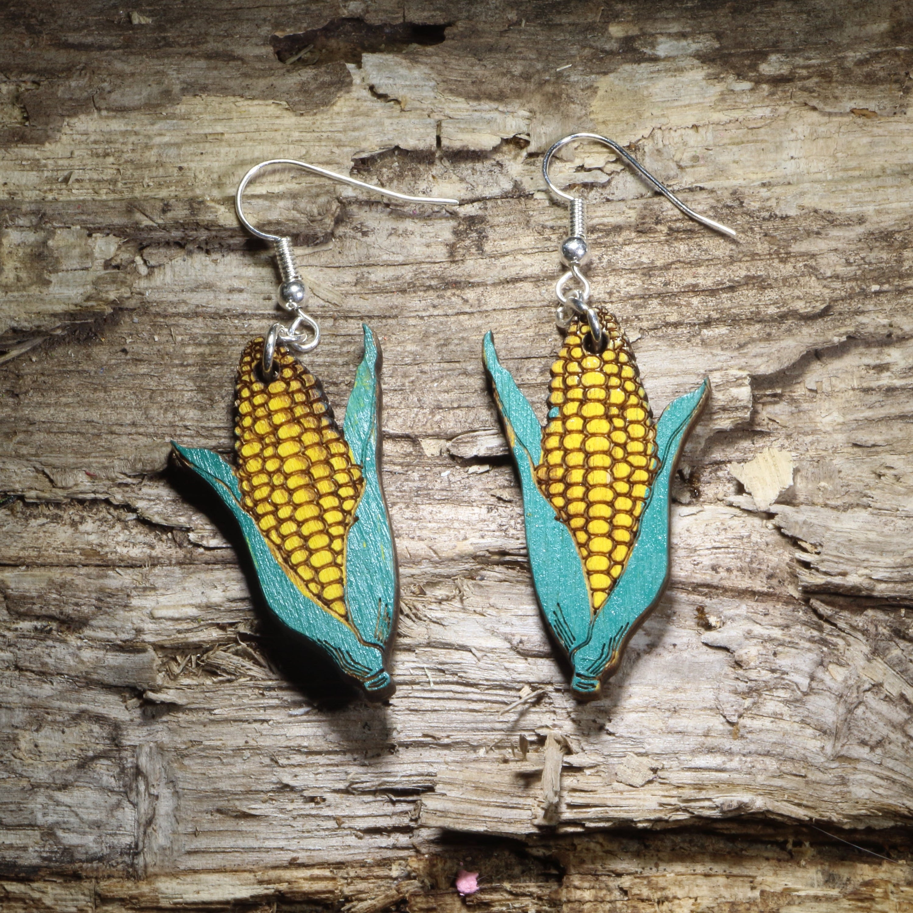 Handcrafted corn on the cob wooden dangle earrings featuring hand-painted golden yellow kernels and green husks. Lightweight wooden food earrings with hypoallergenic .925 sterling silver hooks, perfect for farmers, gardeners, vegetable lovers, county fairs, harvest festivals, Thanksgiving, Midwest pride, and farm-to-table enthusiasts.