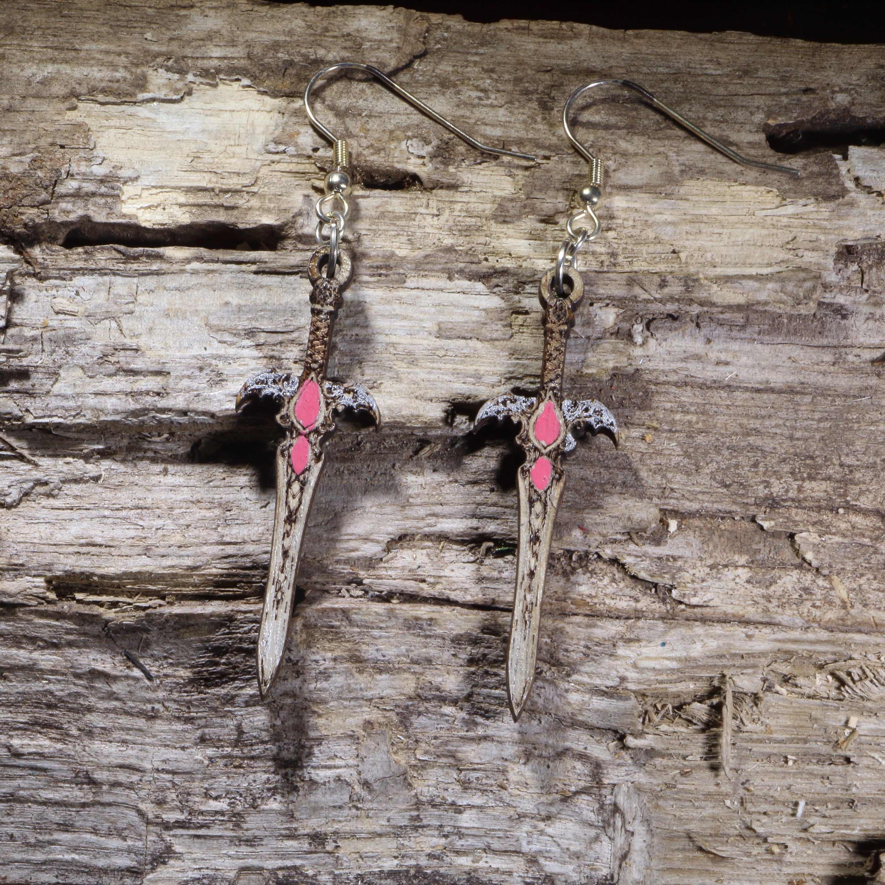Handcrafted fantasy sword wooden dangle earrings featuring an ornate medieval blade with pink gemstone accents and detailed crossguard. Lightweight laser-cut wooden earrings with hypoallergenic .925 sterling silver hooks, perfect for fantasy fans, RPG gamers, cosplay, medieval enthusiasts, Renaissance festival outfits, and sword collectors.