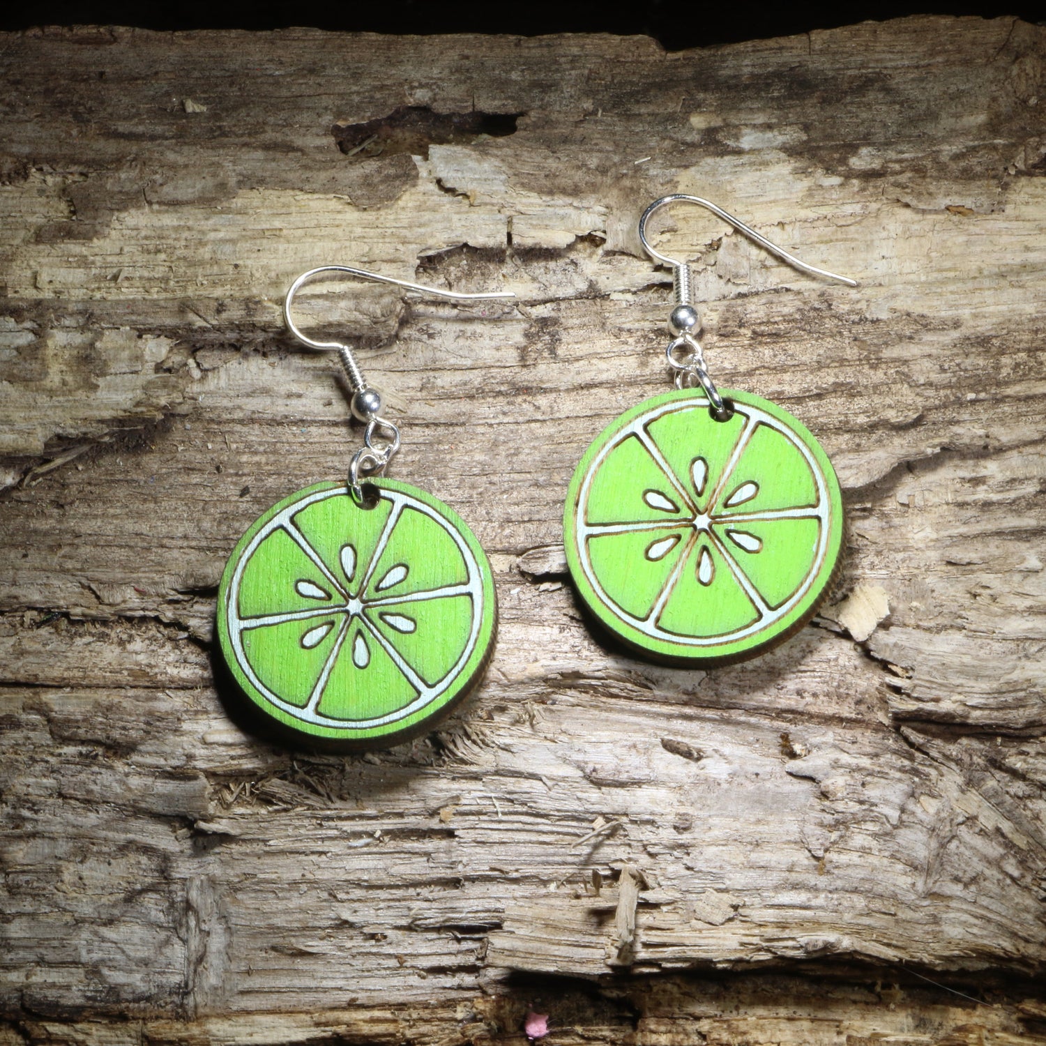 Handcrafted lime slice wooden dangle earrings featuring vibrant hand-painted green citrus slices. Lightweight wooden fruit earrings with hypoallergenic .925 sterling silver hooks, perfect for margarita lovers, bartenders, tropical vacations, summer outfits, citrus fans, taco nights, and fun foodie accessories.