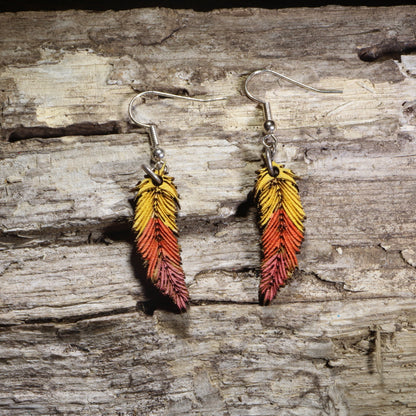 Handcrafted ombré feather wooden dangle earrings featuring hand-painted yellow, orange, and red gradient feathers with engraved detailing. Lightweight laser-cut wooden earrings with hypoallergenic .925 sterling silver hooks, perfect for boho fashion, autumn accessories, nature lovers, festival wear, and colorful handcrafted jewelry.